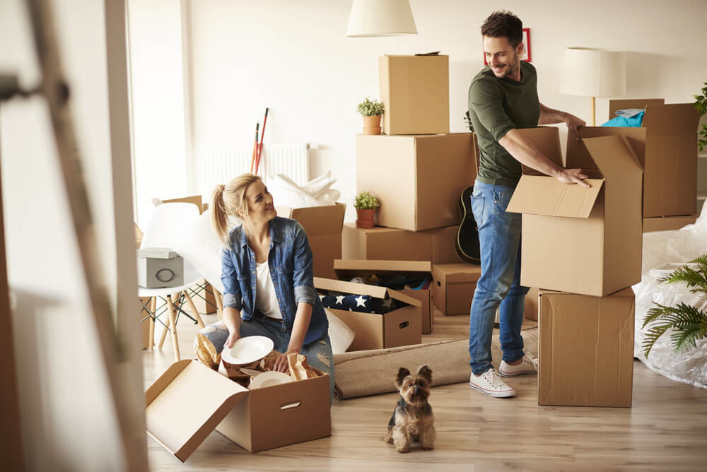 A young couple getting ready to move in by organising their belongings into boxes