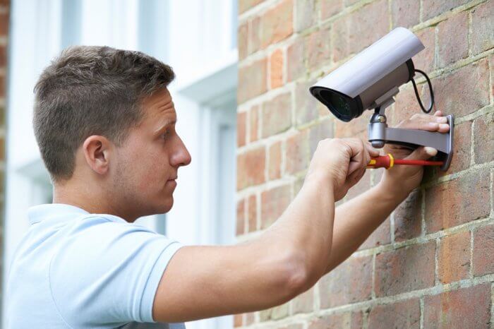 A young man installing security camera to help secure his home against burglary