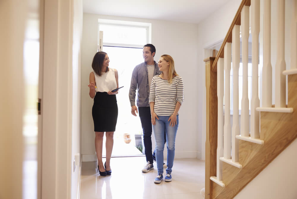 A young property investor couple looking at potential home and asking real estate agent what is landlord insurance