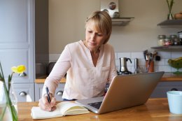 woman in her kitchen writing a list of her contents for insurance purposes