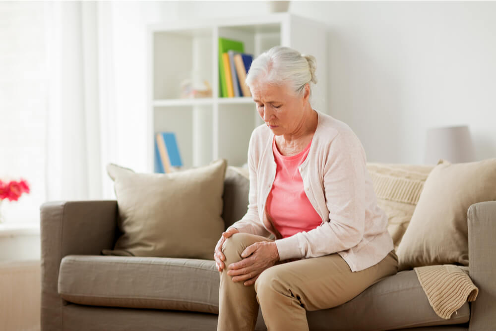 Older woman clutching knee in pain wondering if she’s covered by gold health insurance