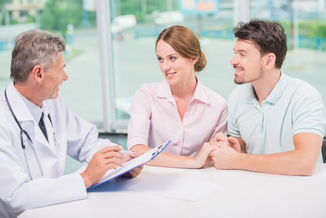 couple talking about health insurance with doctor