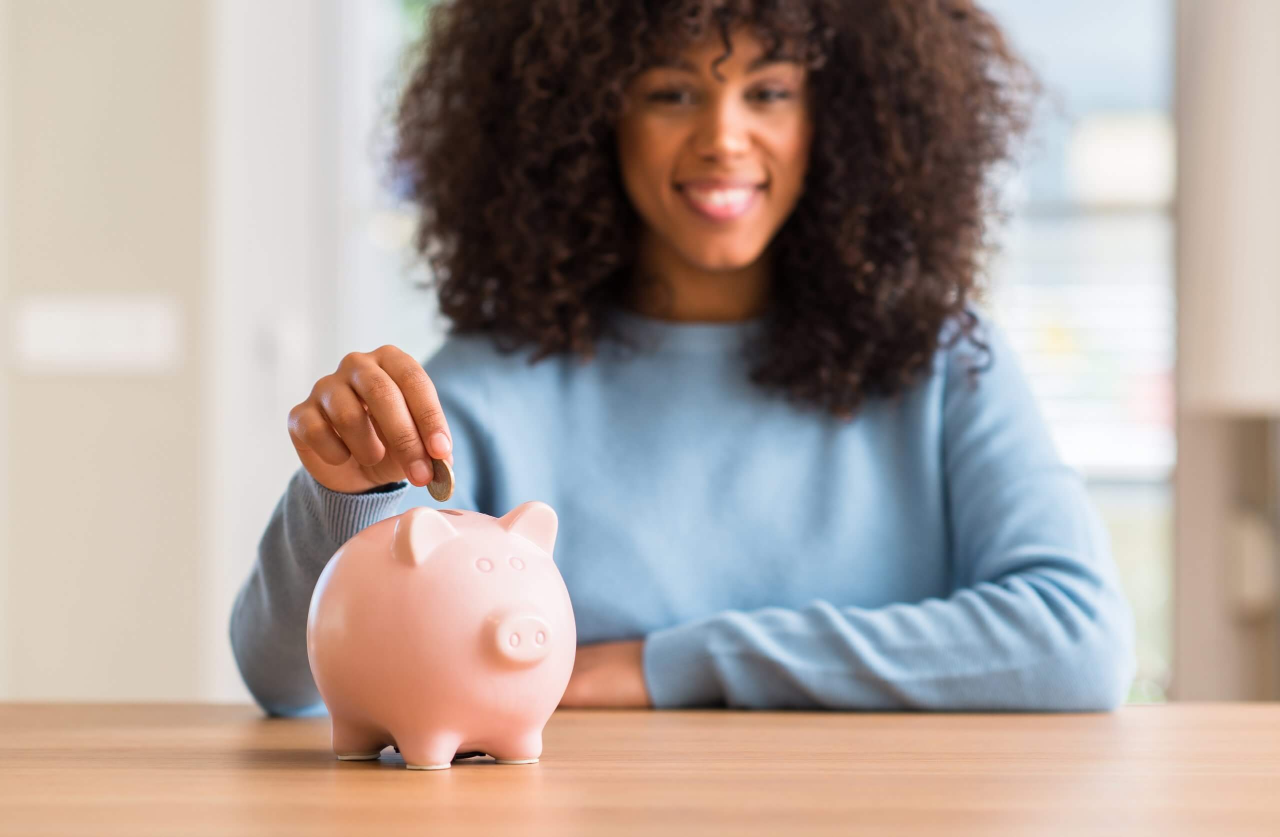 Woman putting money in piggy bank