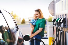 Woman holding baby while refuelling car