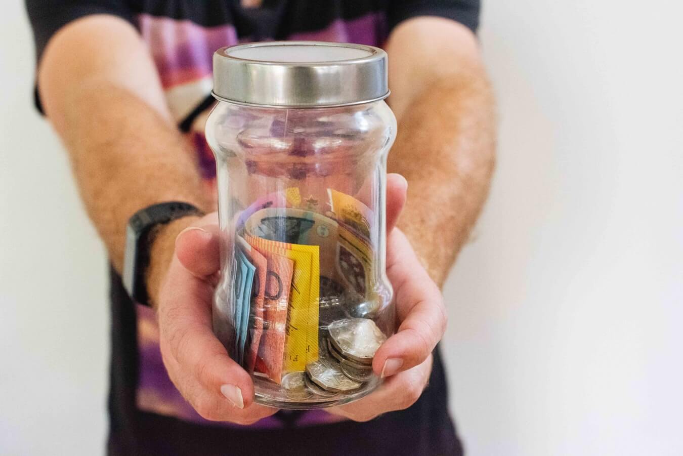 A man holding a jar of Australian money