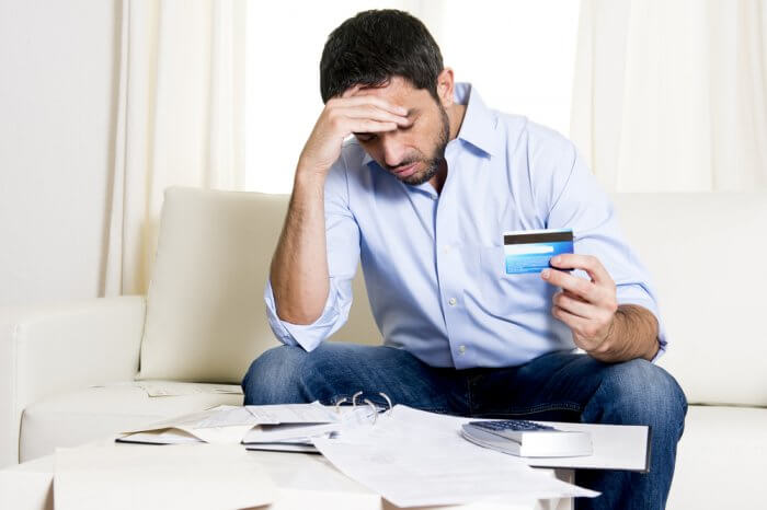 man paying off credit card debt holding head