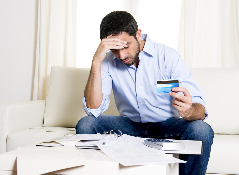 man paying off credit card debt holding head