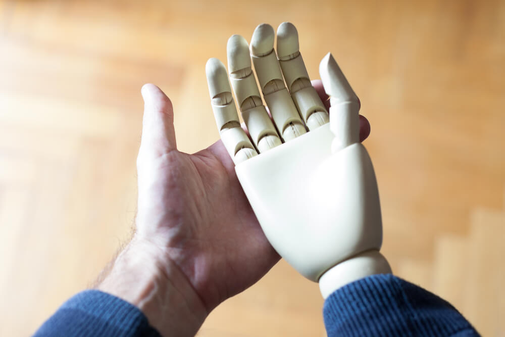 a man’s hand holding a prosthetic hand
