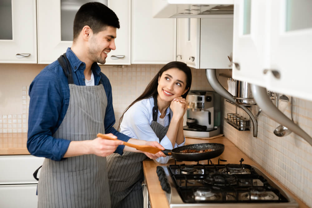 A couple cooking over a gas cooktop
