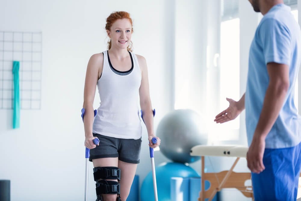 a female patient on crutches walking towards a physiotherapist