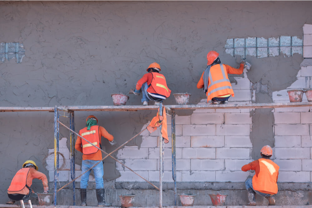 Construction workers plastering a wall.