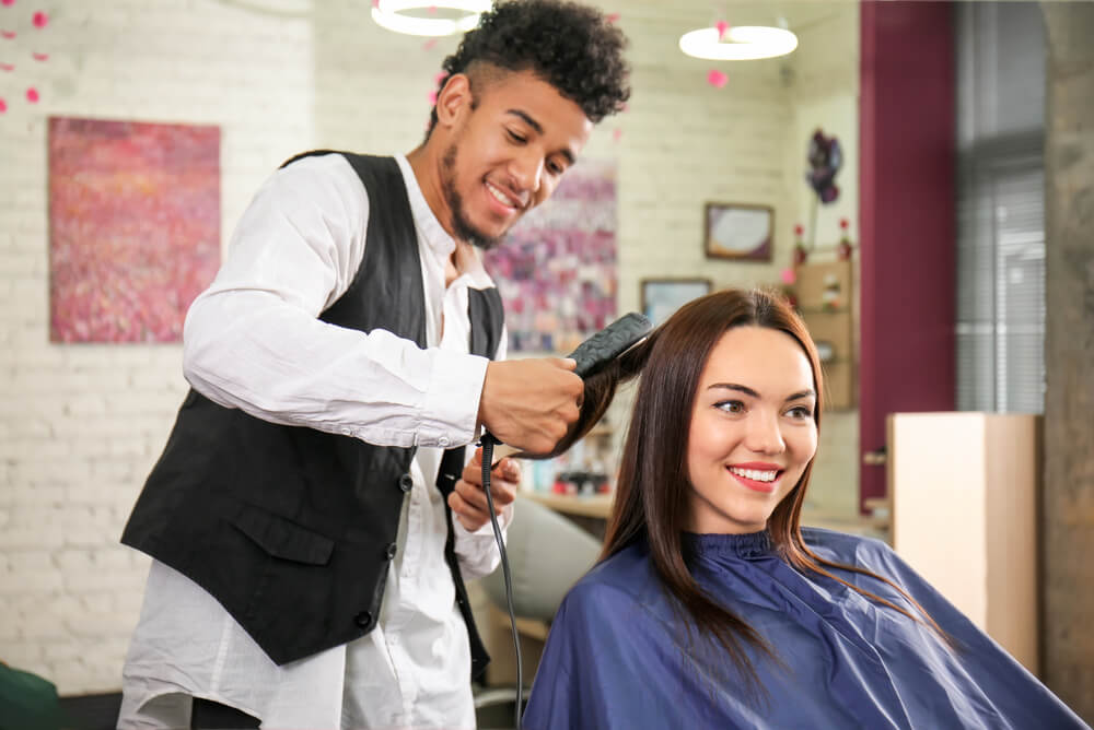 Male hairdresser with business insurance working with female client
