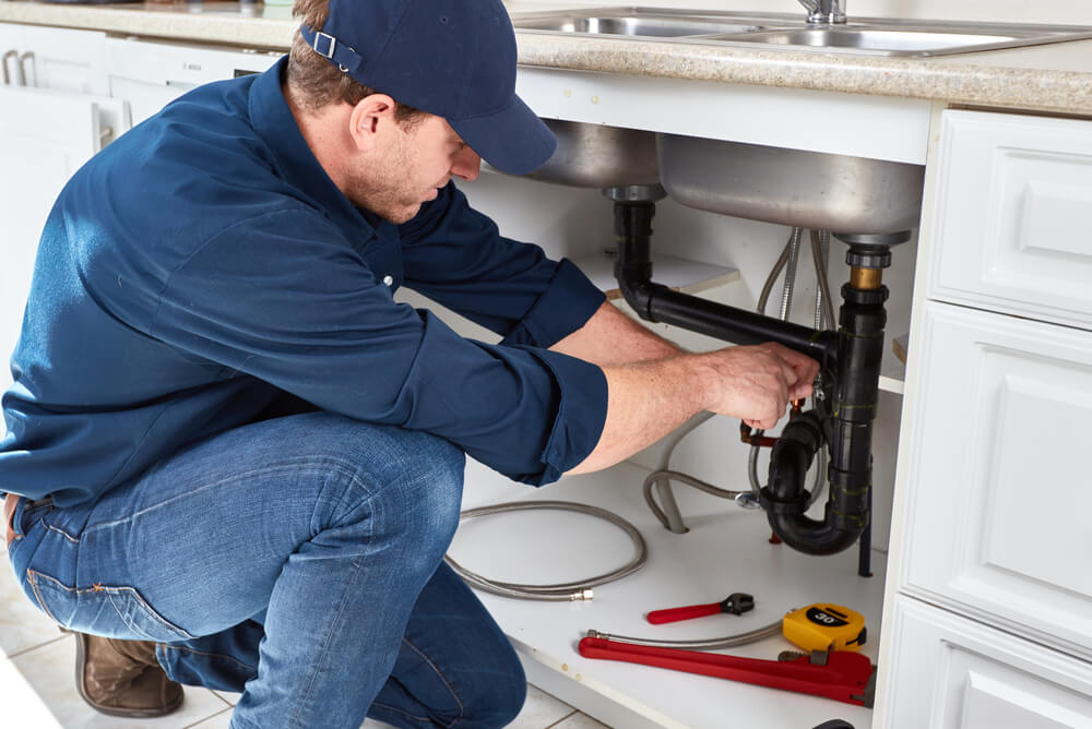 A plumber fixing sink pipes.