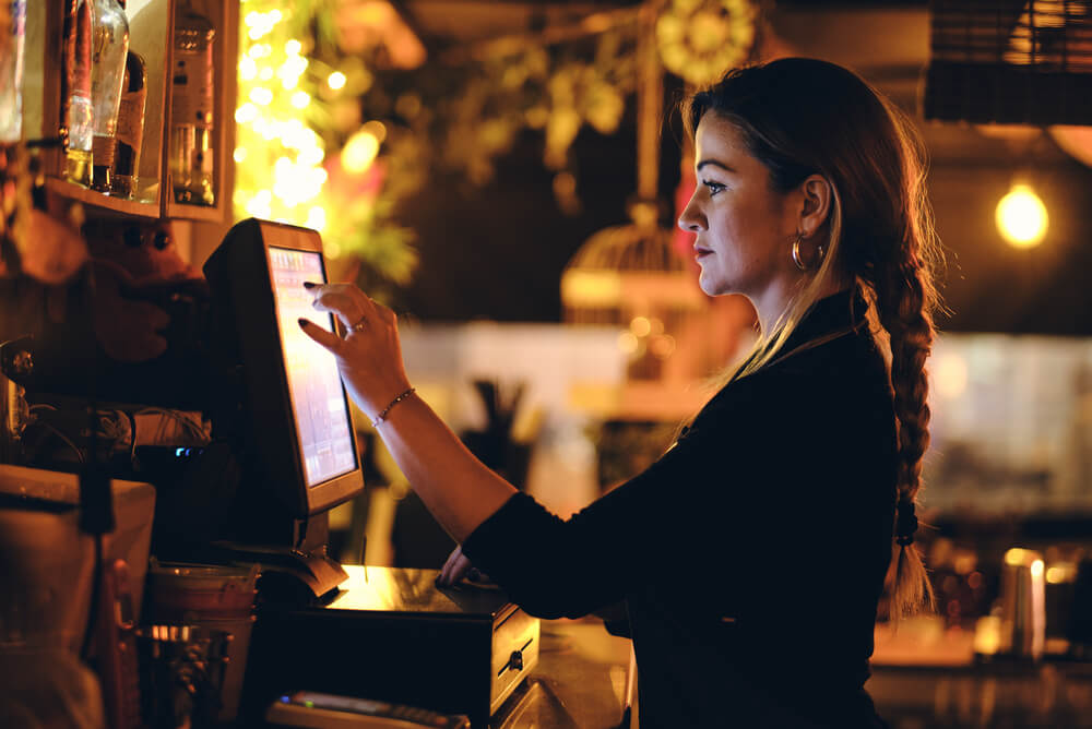 a waitress processes an order at the cash register of a bar