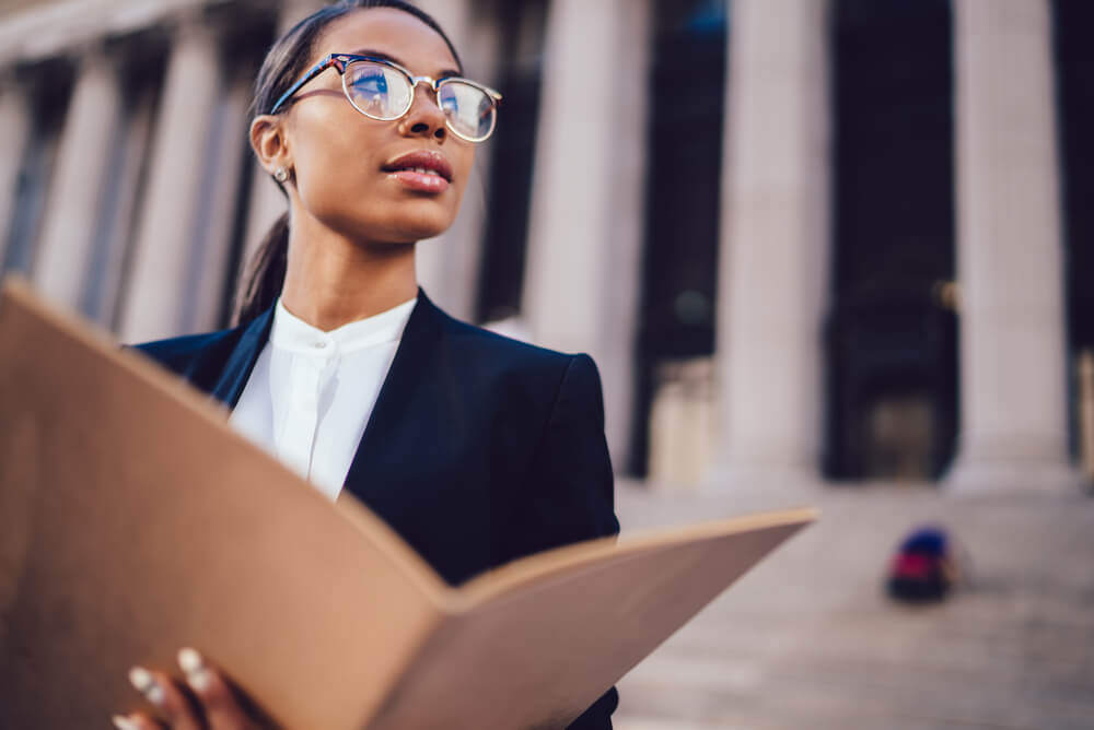 A businesswoman holding a book open outside a court building