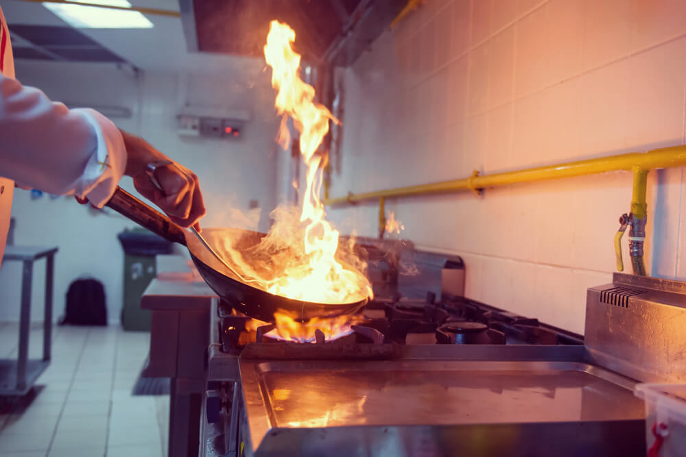 a chef using a commercial gas stove at a food business