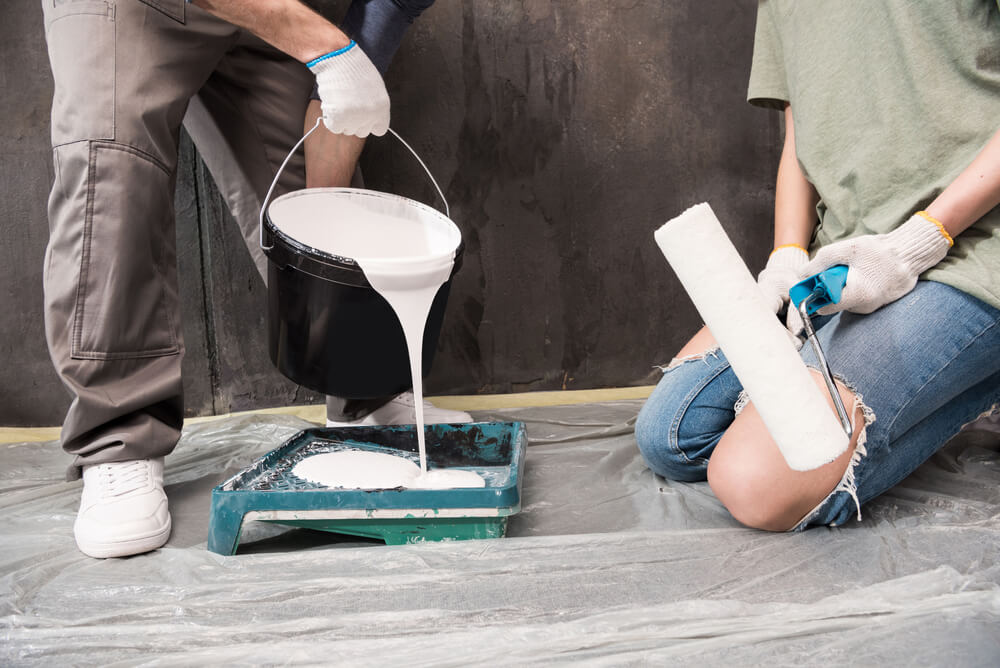 a couple pouring paint into a tray