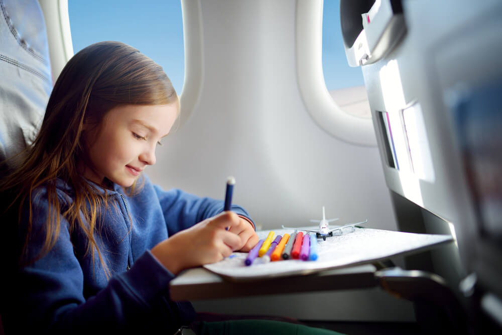 a girl colouring-in while flying on a plane