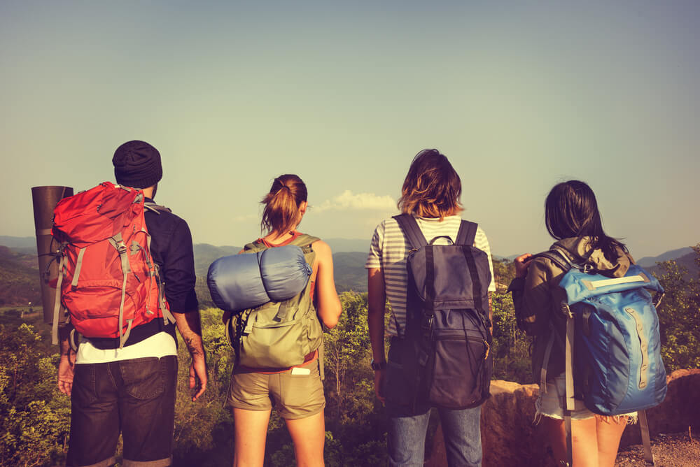 group of backpackers at the beach with travel insurance