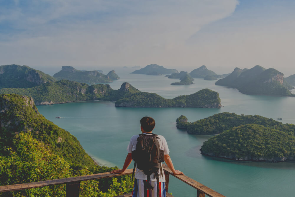 Man covered by travel insurance for Thailand, looking at a view of archipelagos 