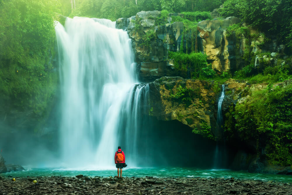 a man backpacking in South America at a waterfall in Ecuador