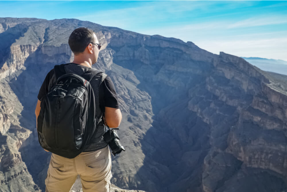 a male tourist with backpack and camera enjoying view of Wadi Ghu in Oman