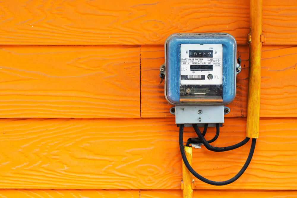 An electricity meter on an orange wooden wall