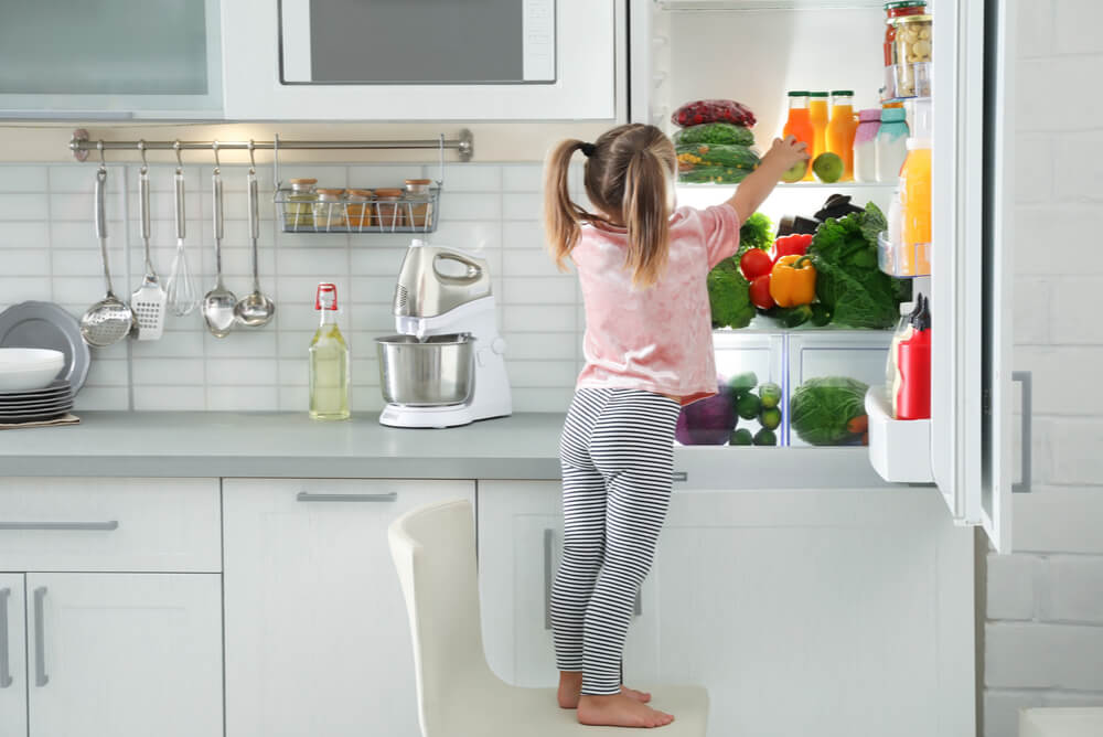young girl looking in refrigerator freezer