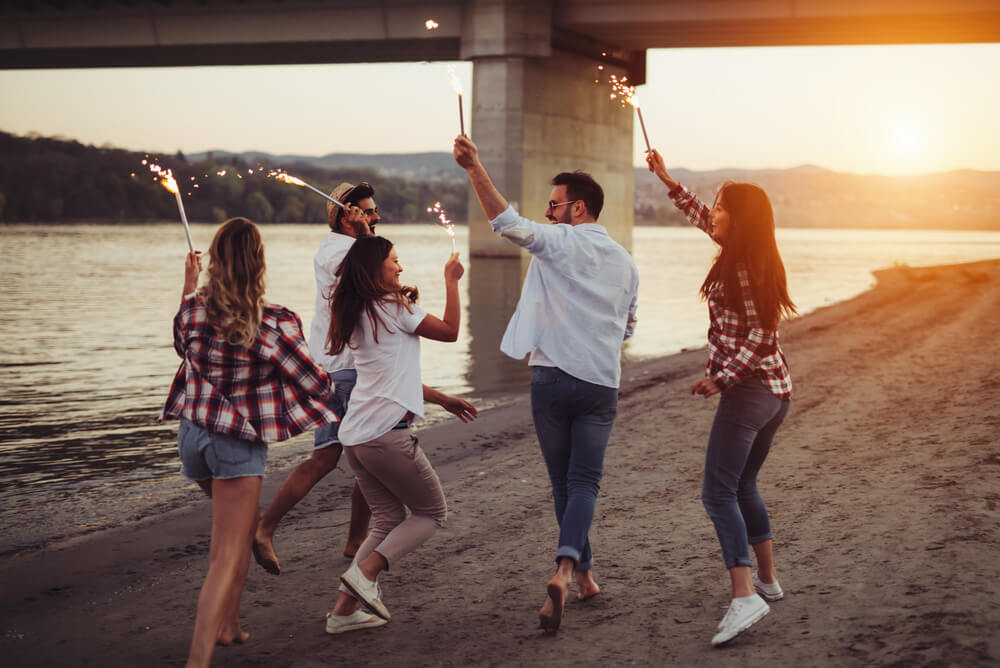 a group of travellers enjoying an evening beach walk with sparklers