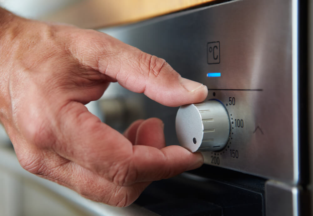 a hand adjusting the control knob on an oven