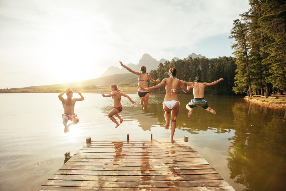 backpackers jumping into a lake