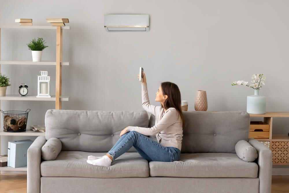 Woman adjusting the airconditioner to save electricity