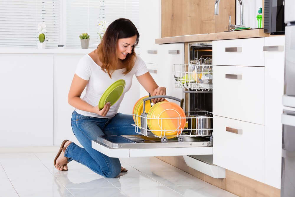 woman using the dishwasher after checking its power consumption