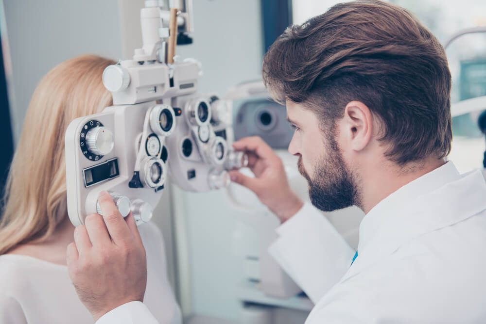 young woman getting eye test at optometrist covered through optical health insurance