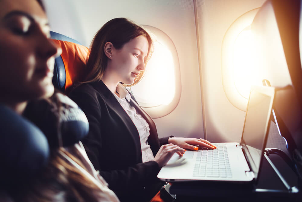 businesswoman working on a laptop seated in a plane