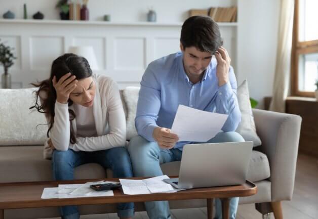 Young couple looks over bills in frustration