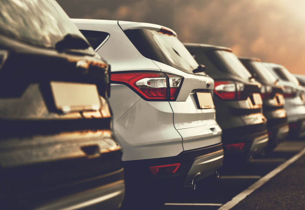 a number of electric SUV’s parked in a saleyard at sunset