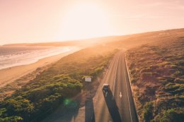a car driving down Great Ocean Road at sunset