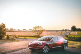Red Tesla Model 3 parked to the side of the road in rural Australia