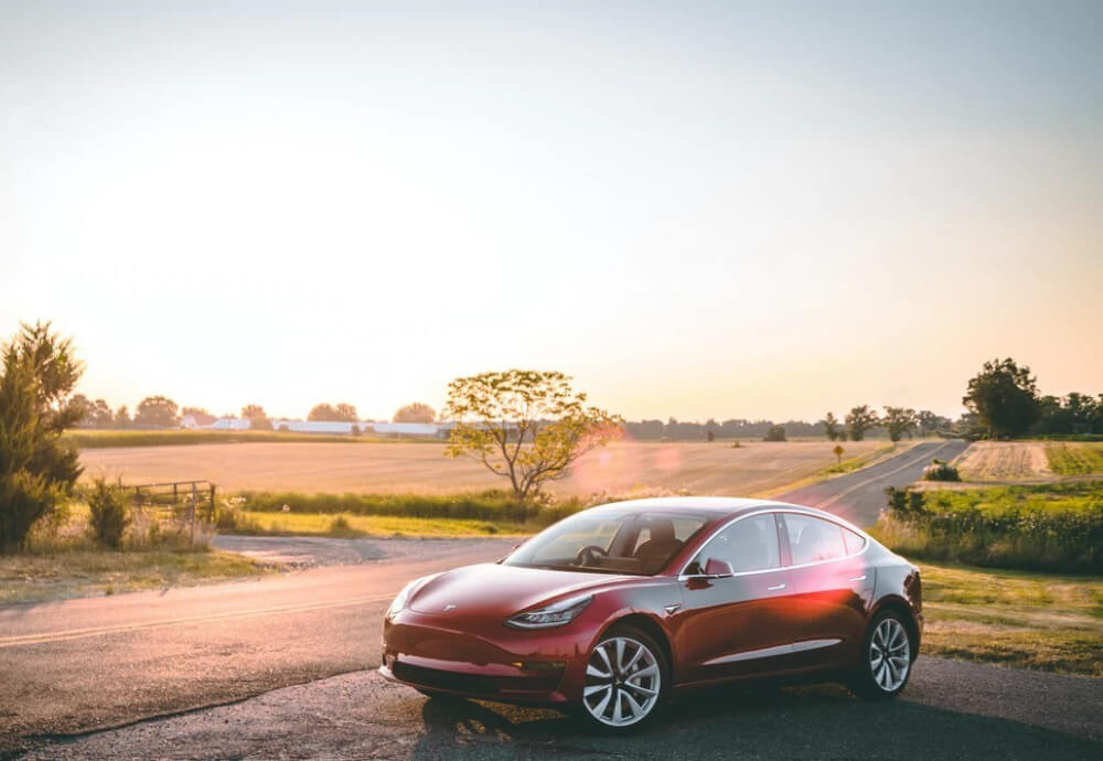 Red Tesla Model 3 parked to the side of the road in rural Australia