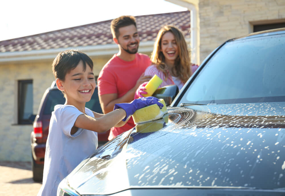 a family washing their car in the driveway