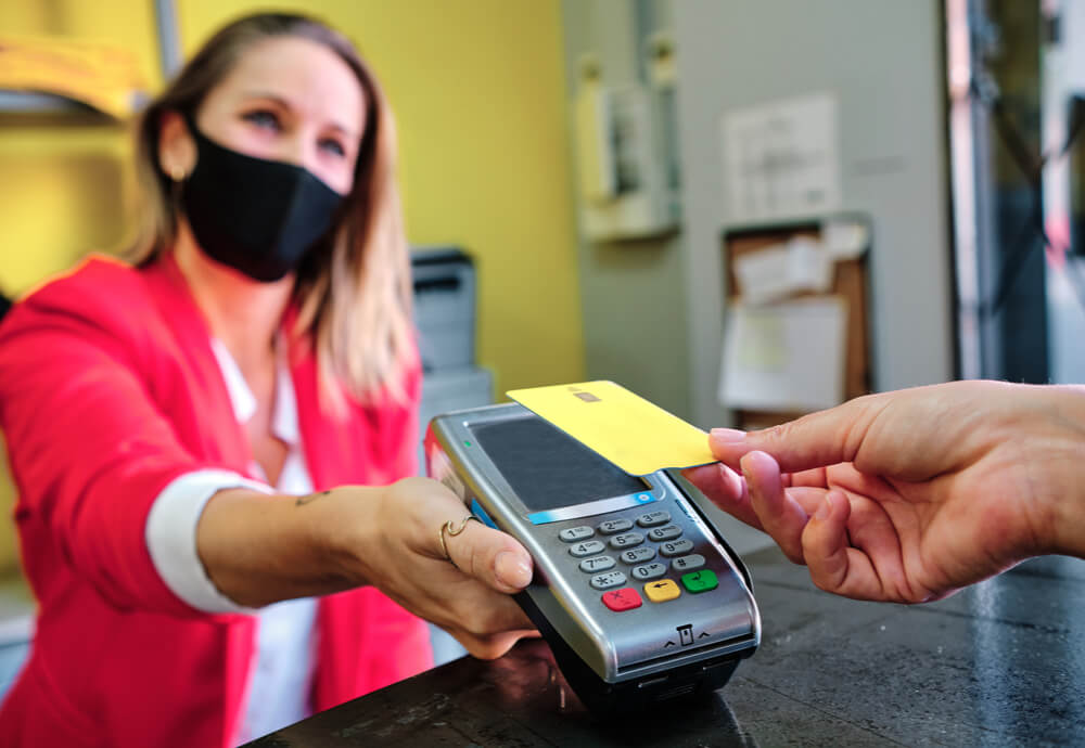 Masked woman holding eftpos machine