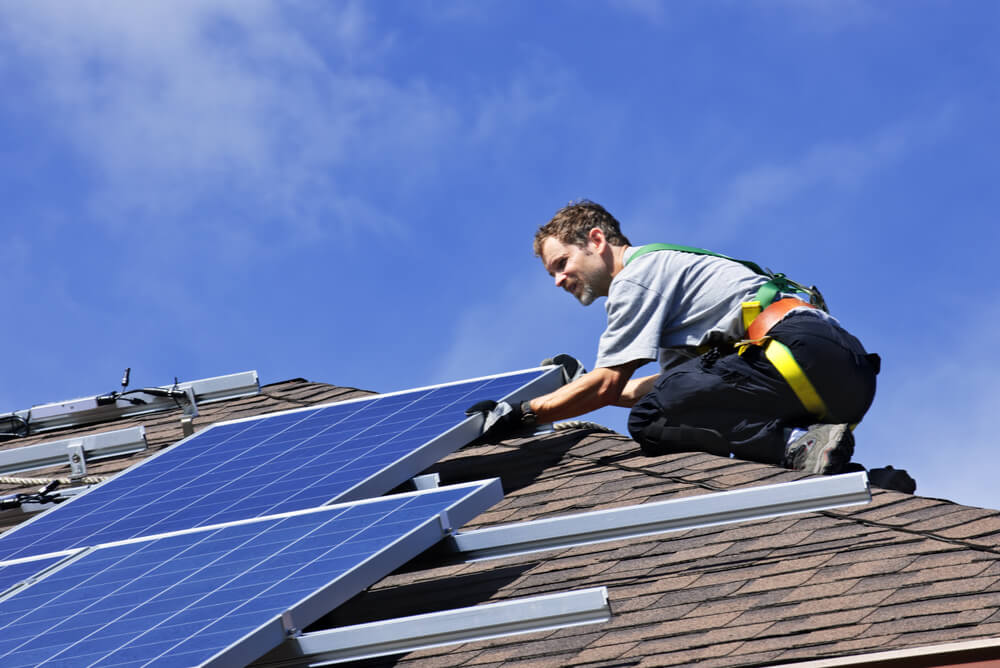 man installing solar pv system on roof