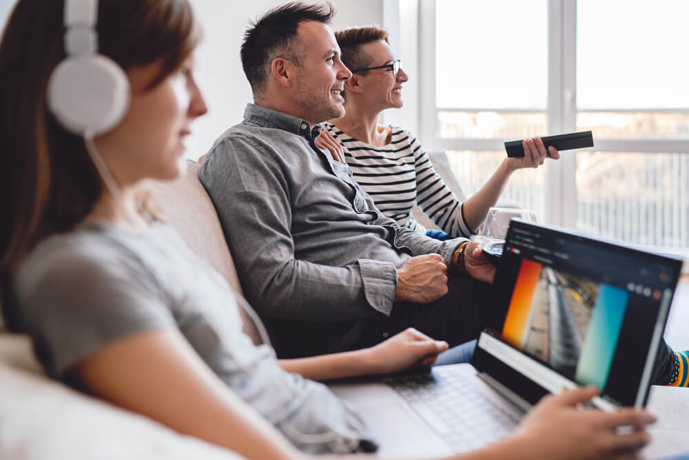 parents watch TV while daughter is on laptop