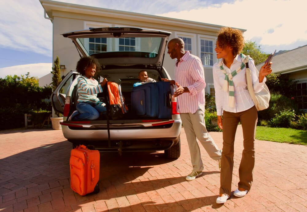 Alt tag: a family hopping into their car with suitcases