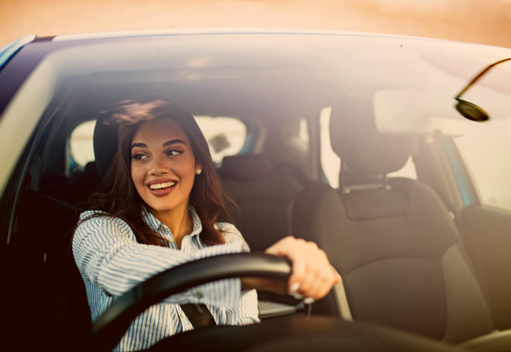 a woman smiling as she drives a car