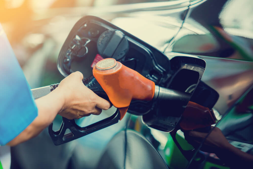 a man’s hand refuelling car with orange petrol nozzle