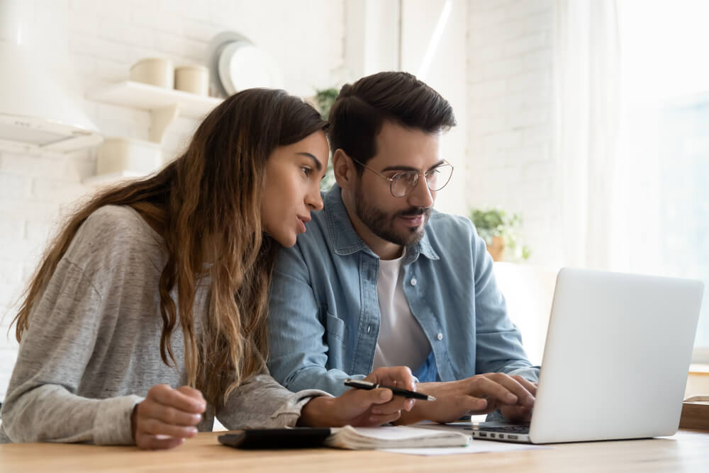 a man and woman looking at the average cost of car insurance in Australia on a laptop