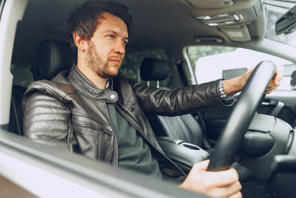 a man in leather jacket behind the wheel of his electric car