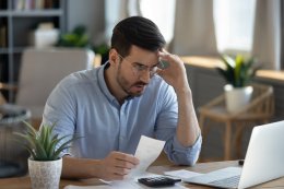 a man sitting in his office looking at expensive car bills on his computer